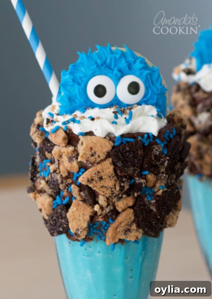 Two fully assembled Cookie Monster Freak Shakes, vibrant blue with whipped cream, sprinkles, crushed cookies, and Cookie Monster cookie toppers, ready to be enjoyed.
