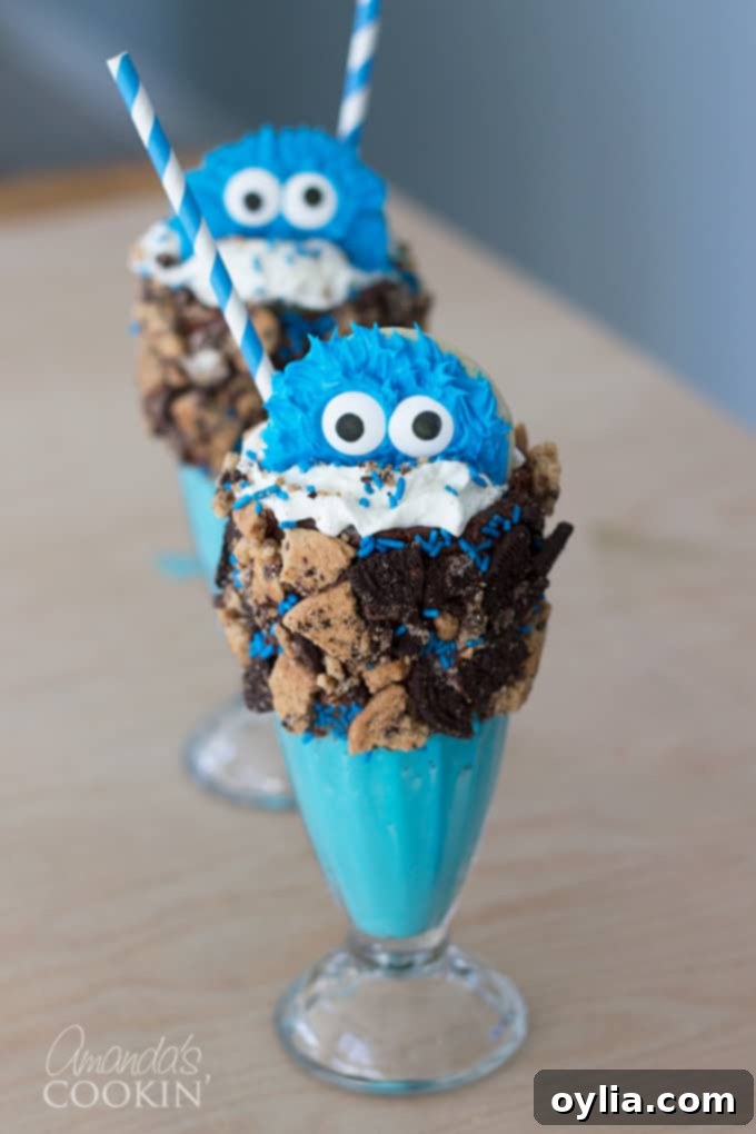 A vibrant blue Cookie Monster Freak Shake, generously topped with whipped cream, sprinkles, crushed cookies, and a cute Cookie Monster cookie.