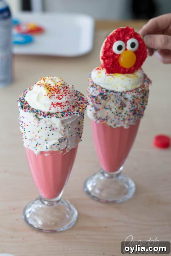 The final step of assembling Elmo Freakshakes: adding the creamy red milkshake to chilled glasses.