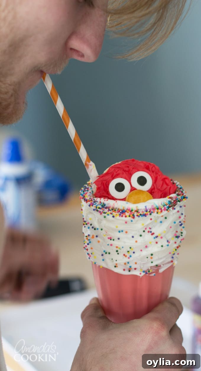 Happy boy enjoying an Elmo Freakshake with a straw, clearly delighted by the fun treat.