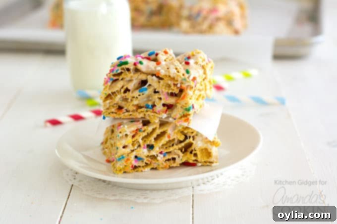 Two freshly cut Funfetti Marshmallow Cereal Bars on a small white plate, ready for a sweet indulgence.