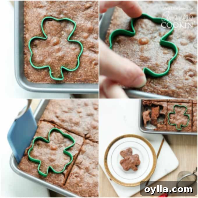 A hand using a shamrock cookie cutter to cut a brownie from a baking pan