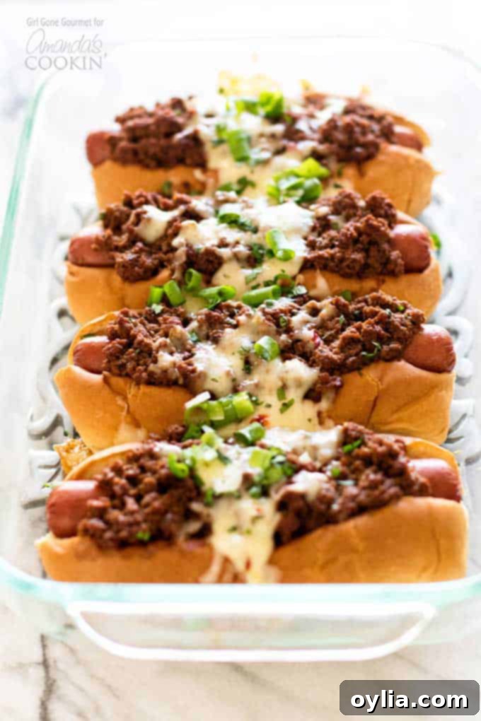Hot dogs topped with a simple and flavorful chili, pepper jack cheese, and fresh green onions - these oven chili dogs are always a crowd favorite! #chilidog #howtomakechilidogs #chilidogrecipe #chilicheesedogs #chili #hotdog #cheese #oven #baked #weeknightdinner #easydinner #easymeals Hot dogs nestled in soft buns, topped with chili, melted pepper jack cheese, and green onions