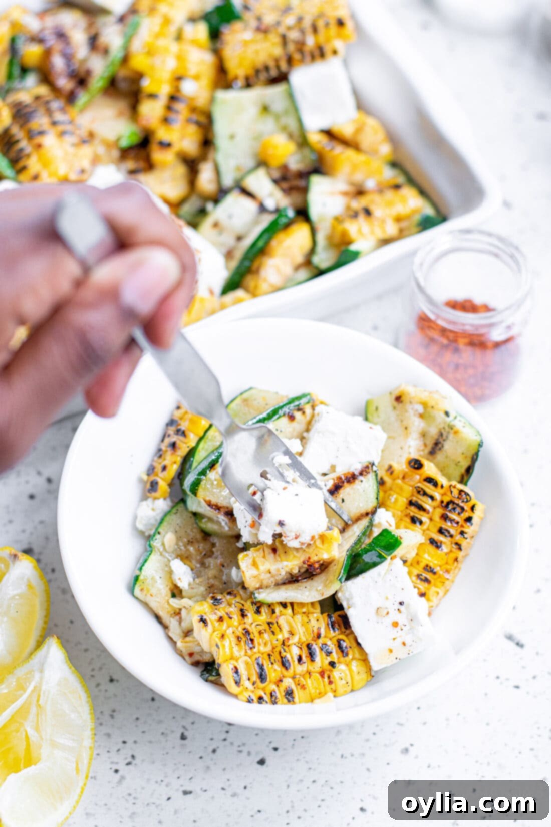 A fork taking a portion of Grilled Corn & Zucchini Salad with Feta from a bowl, highlighting the fresh ingredients