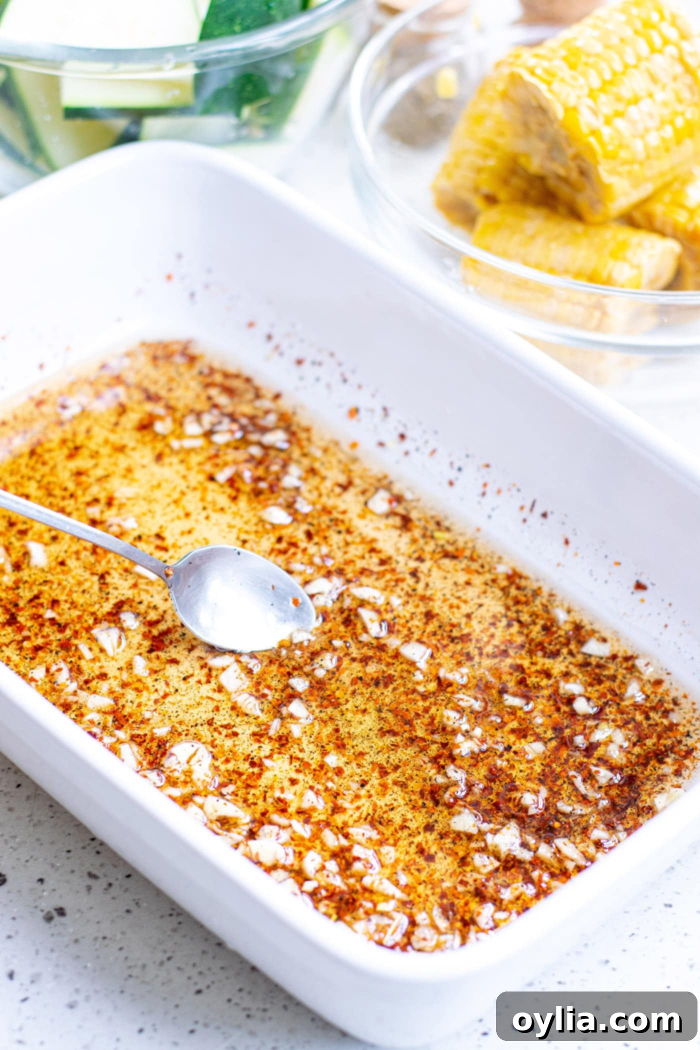 Olive oil mixed with salt, pepper, garlic, and red pepper flakes in a baking dish, ready for vegetables