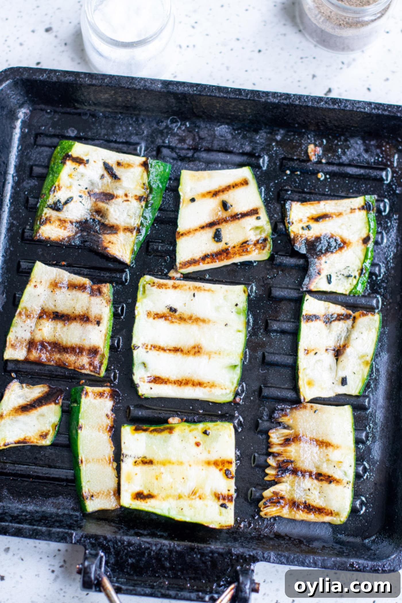 Grilled zucchini slices with visible char marks cooling on a tray after being cooked