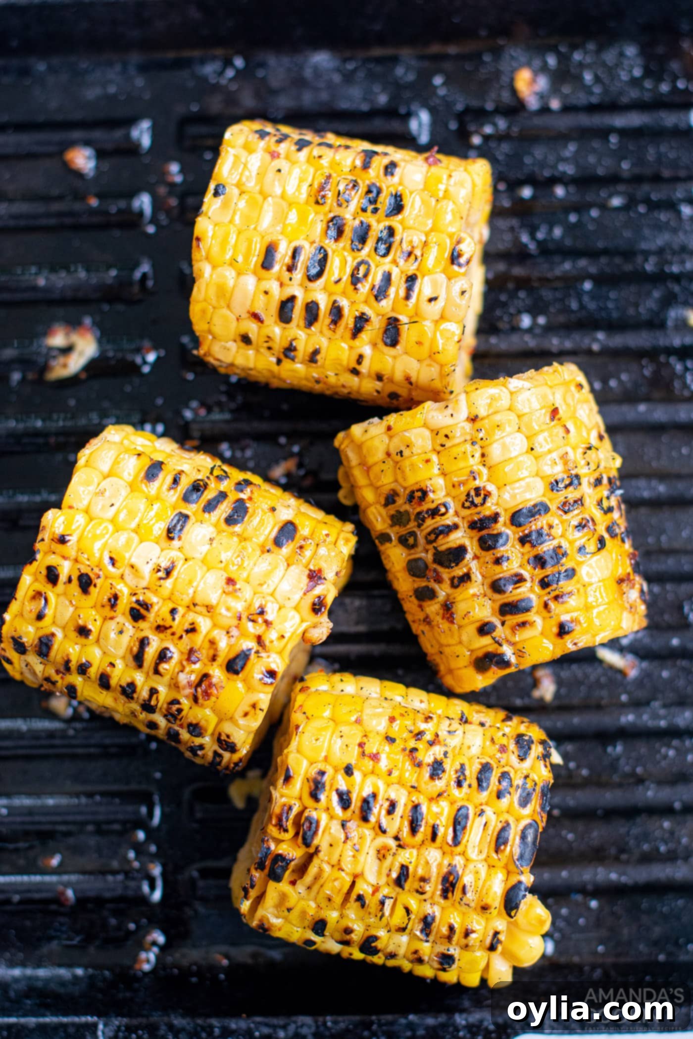 Charred corn cobs on a grill, showing smoky grill marks and cooked kernels