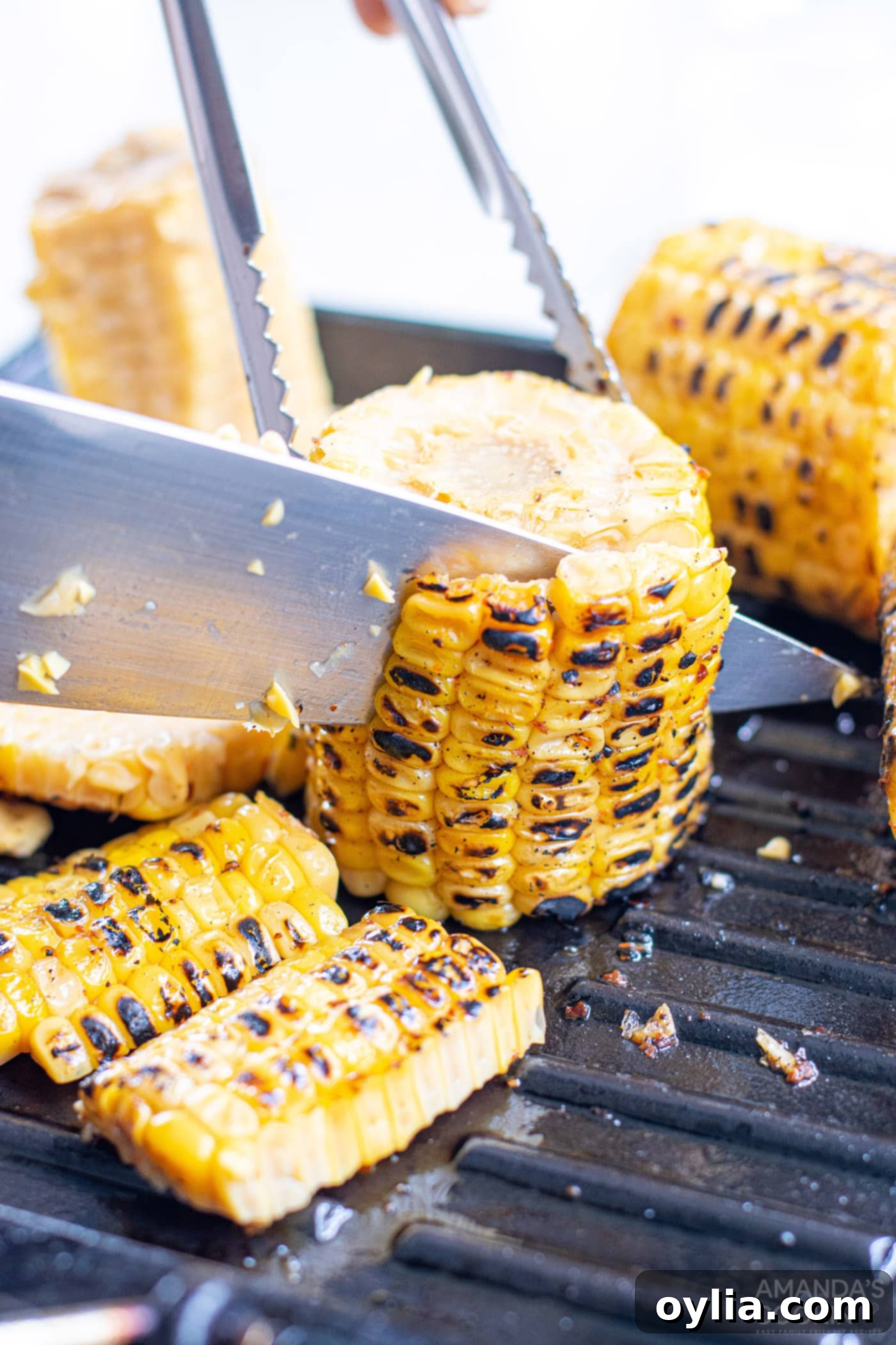 A knife carefully cutting corn kernels off the cob into a bowl, demonstrating the technique
