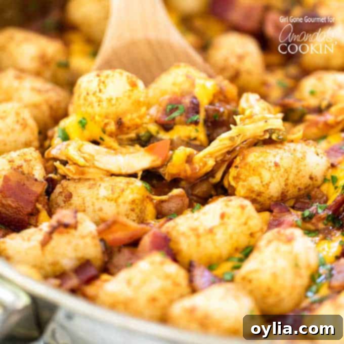 BBQ chicken, tater tots, and bacon in a skillet with wooden spoon