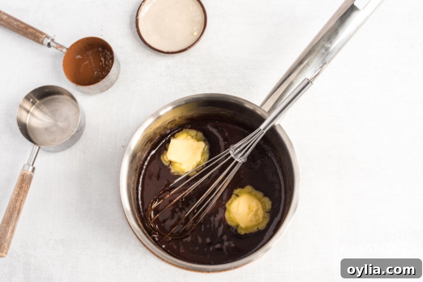 Whisking softened butter into the warm chocolate mixture, creating a rich and smooth ganache for the eclair cake.