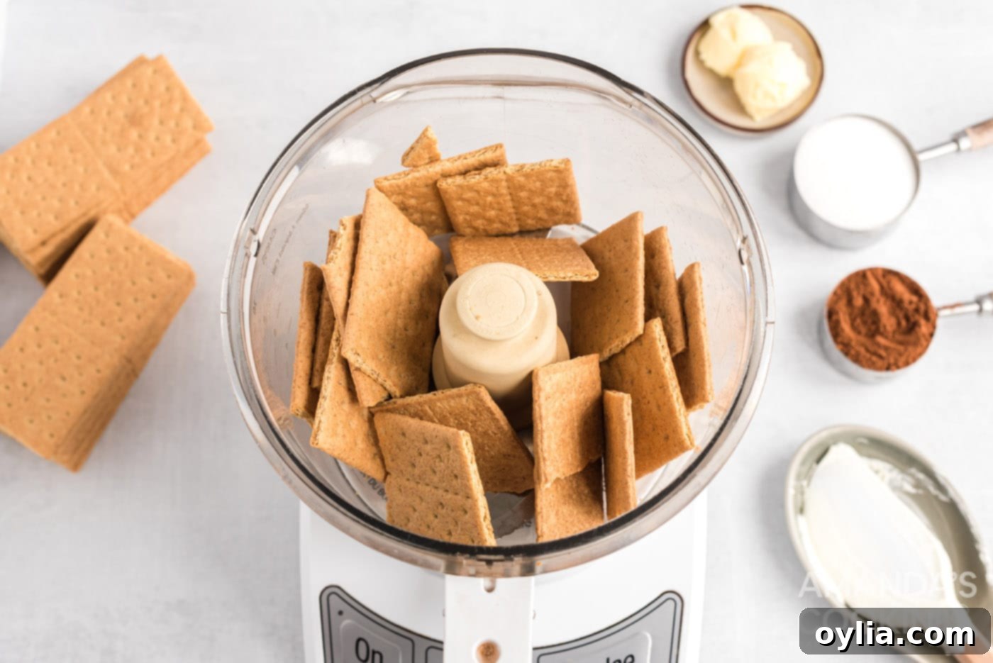Graham crackers being pulsed into fine crumbs in a food processor, which will be used for the top layer of the eclair cake.