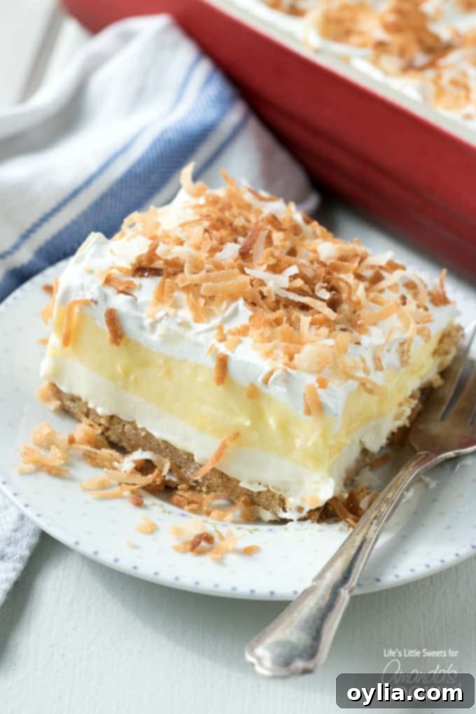 Indulge in this light, creamy, and delicious Coconut Cream Lush, a perfect one-pan dessert for any gathering! Slice of creamy Coconut Cream Lush dessert on a plate, showing distinct layers
