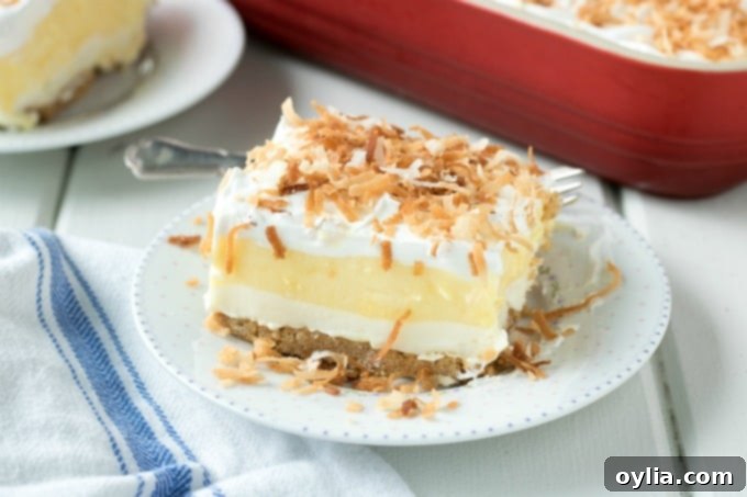 A mouth-watering slice of Coconut Cream Lush, ready to be enjoyed. Single slice of Coconut Cream Lush dessert on a white plate