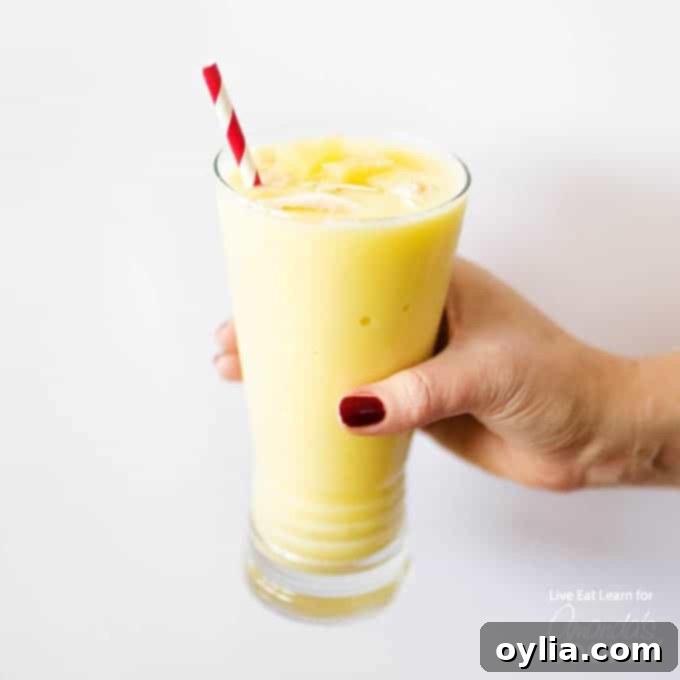 hand holding glass of pina colada smoothie