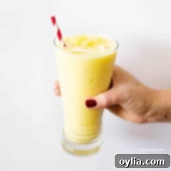 hand holding glass of pina colada smoothie