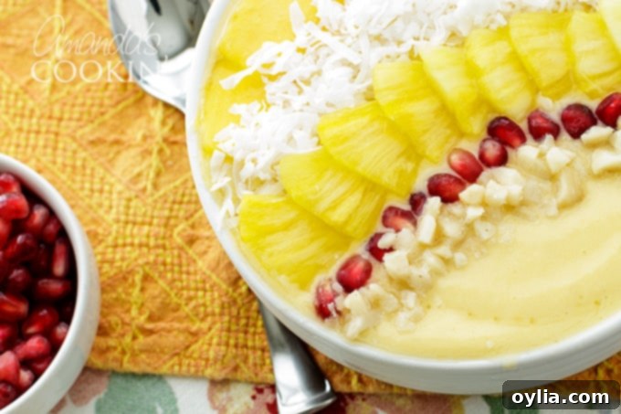 A vibrant Tropical Smoothie Bowl topped with fresh mango, pineapple, shredded coconut, and pomegranate arils, ready to be enjoyed.