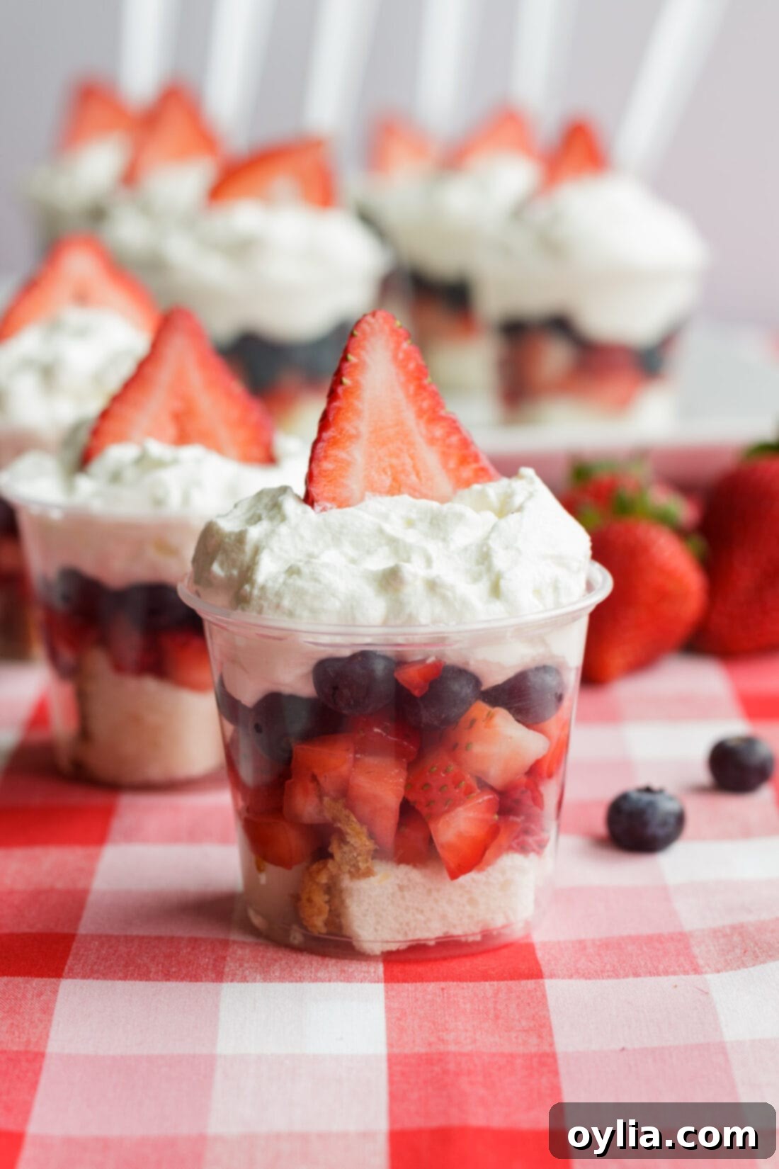 Mini Shortcake Cup with more behind it, showcasing fresh strawberries, blueberries, and whipped cream layers.