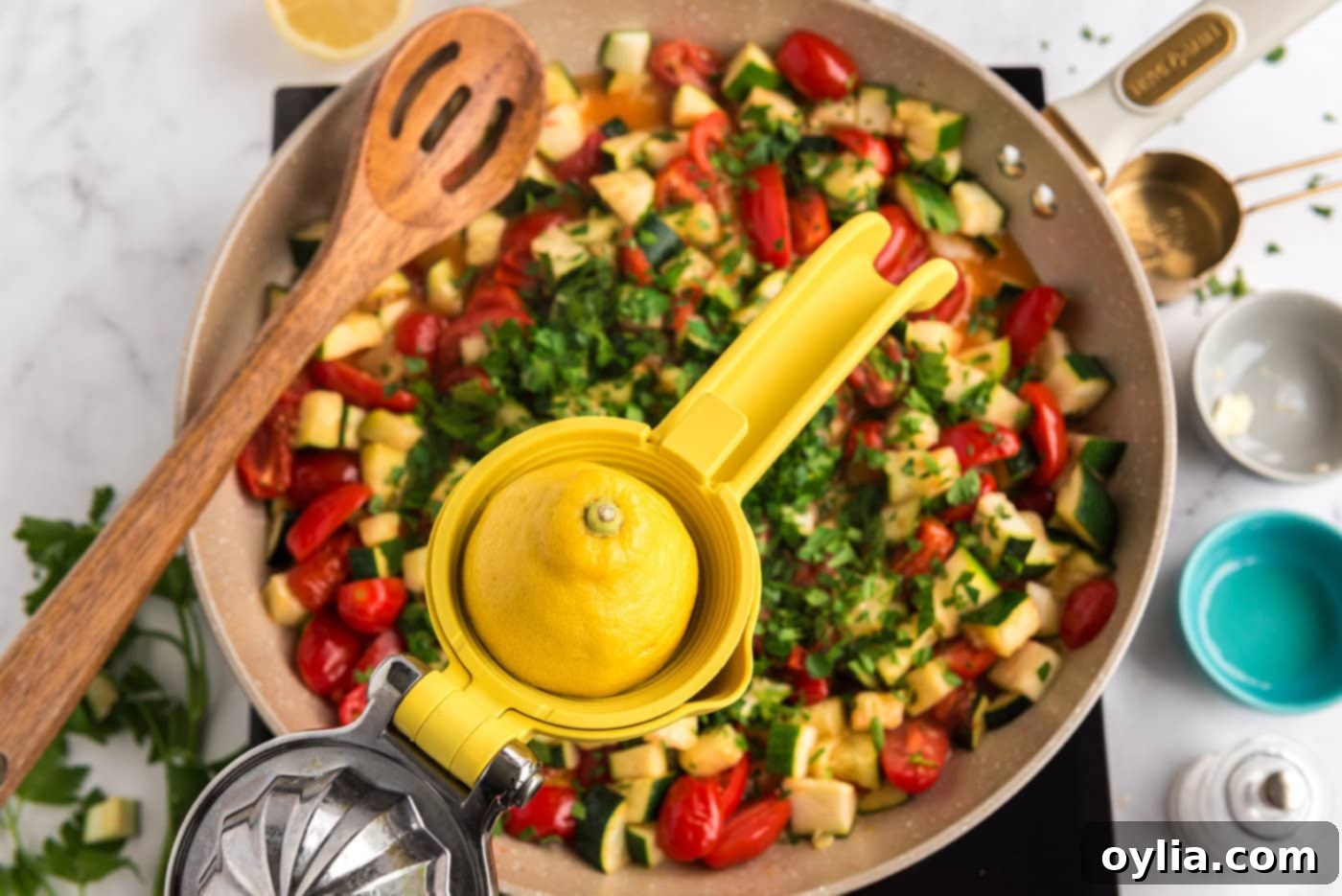 adding lemon juice to a pan of zucchini and tomatoes with fresh parsley