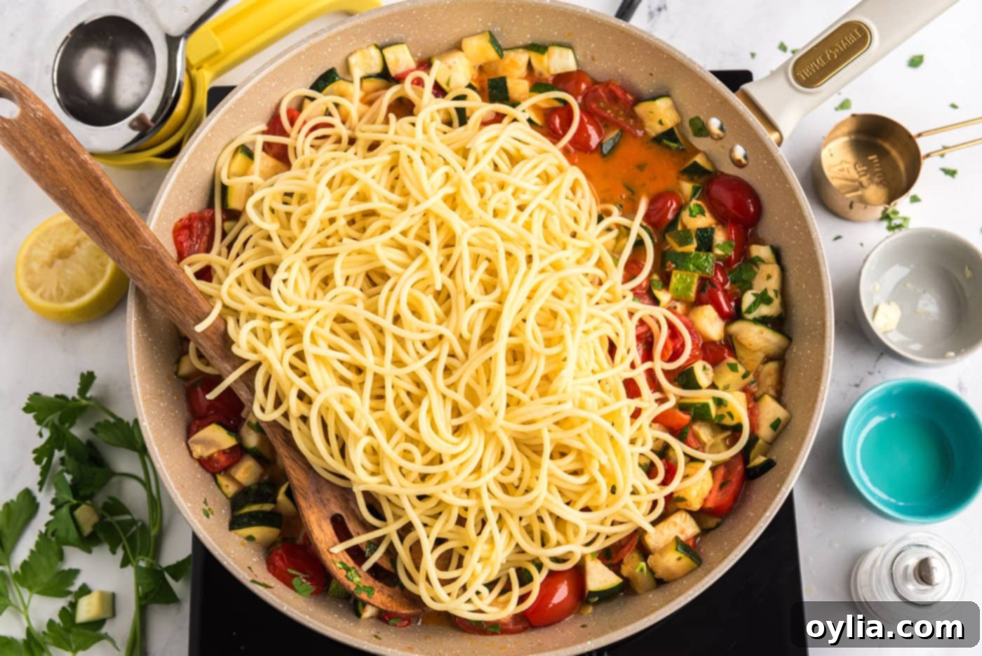 cooked pasta added to skillet with zucchini and tomatoes, ready to be tossed