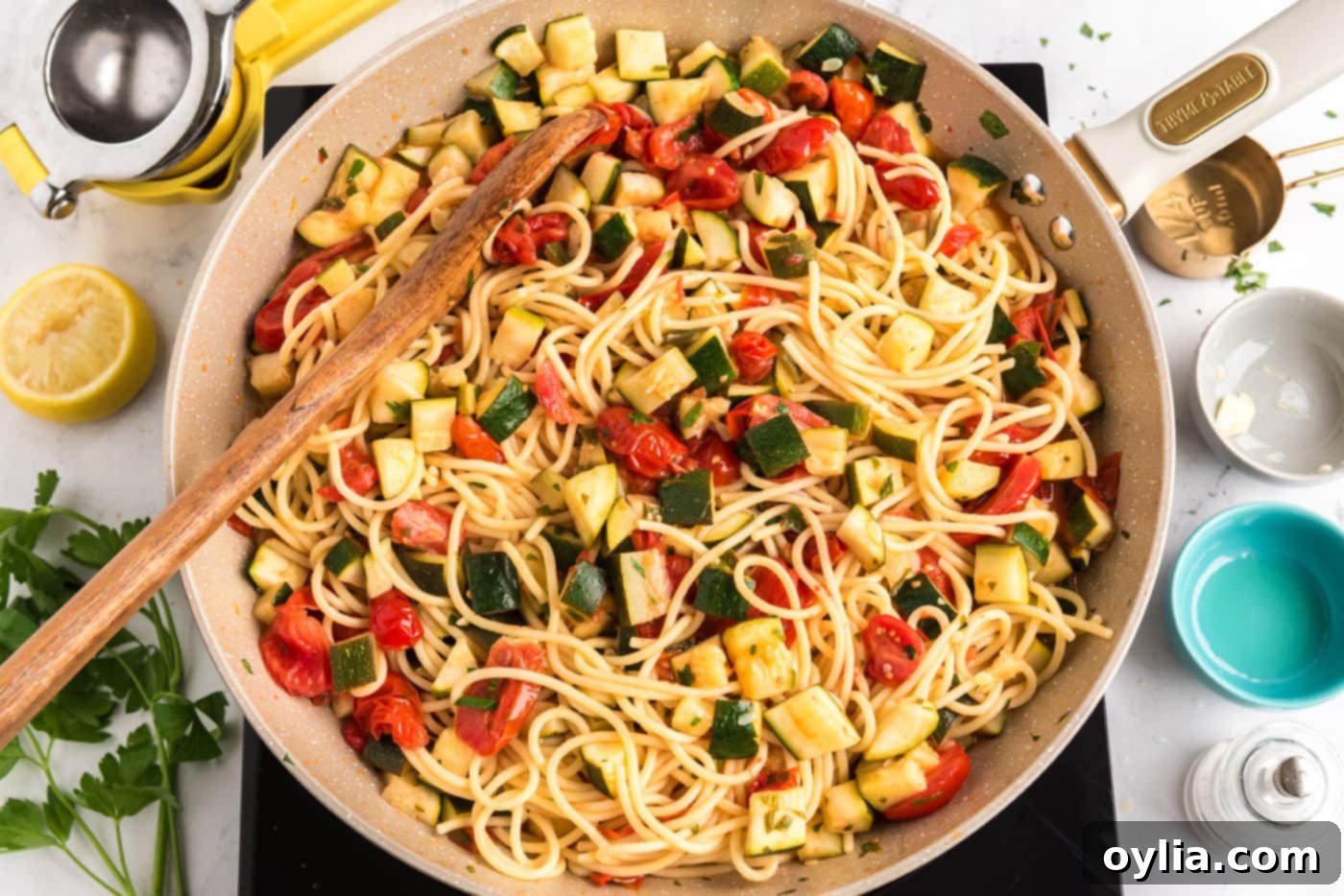 zucchini tomato pasta in a skillet with a wooden spoon, fully mixed and ready to serve
