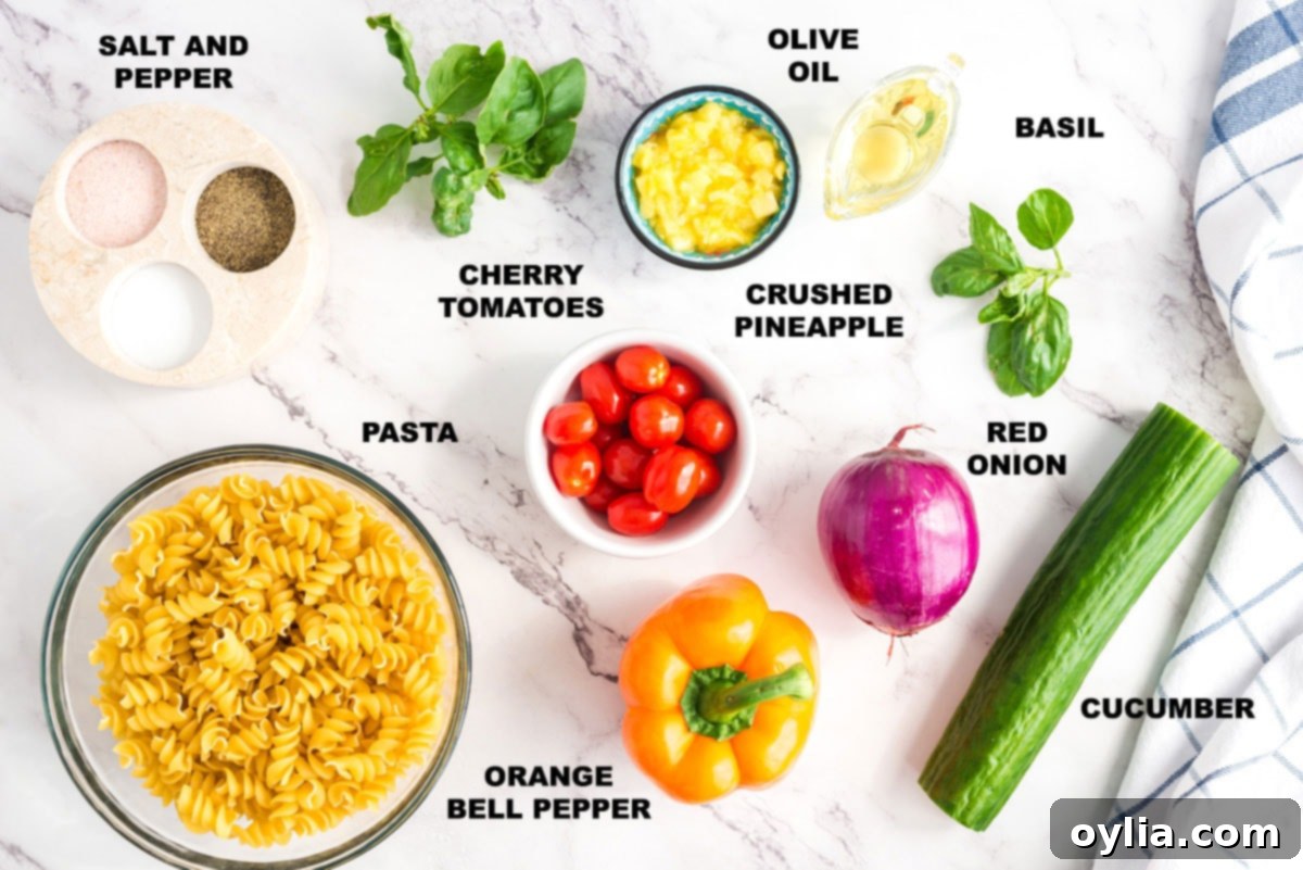 Assortment of fresh ingredients for summer pasta salad including pasta, tomatoes, bell peppers, cucumber, onion, pineapple, and basil.