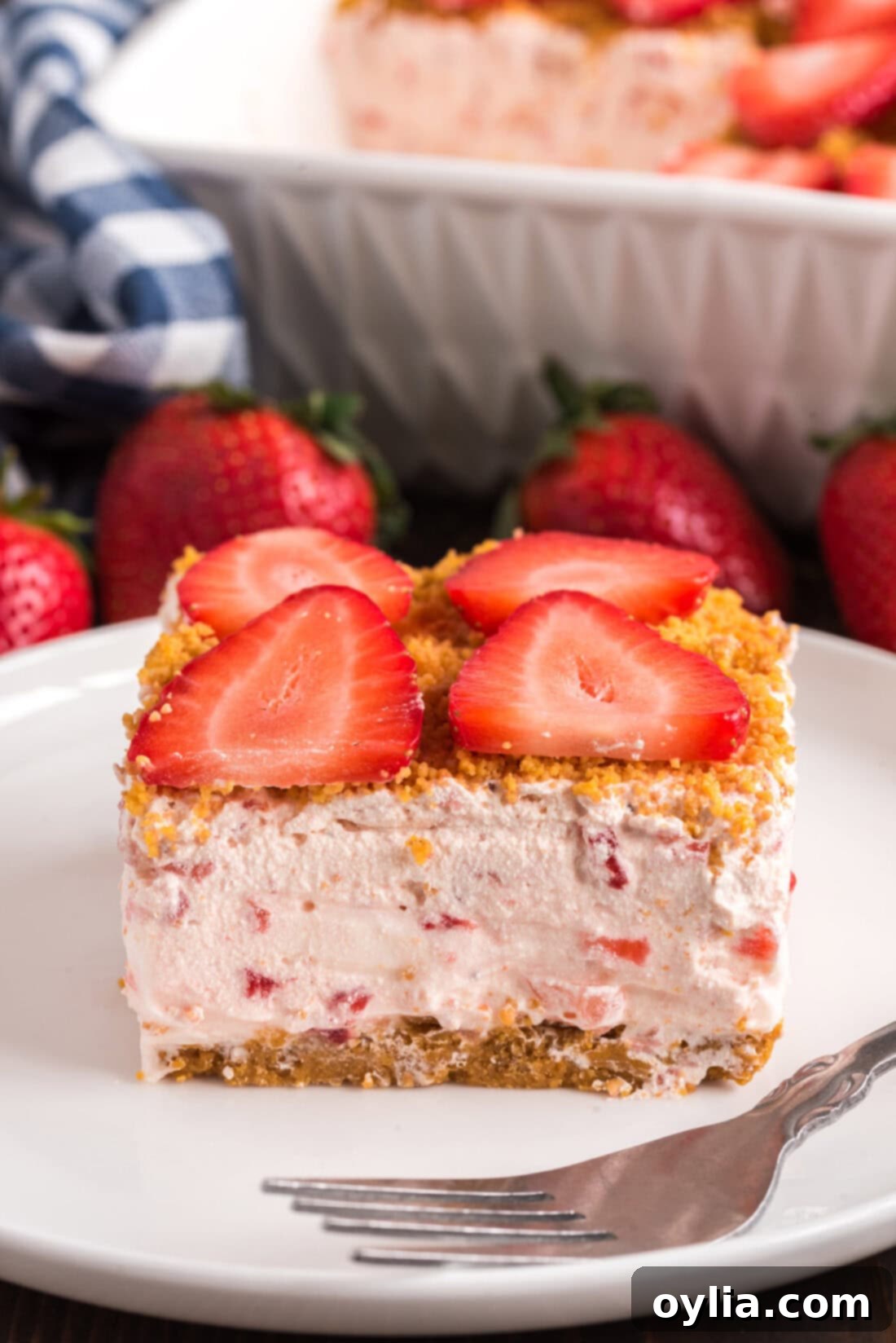 Slice of Strawberry Dream Dessert on a plate with a fork, showcasing creamy layers and fresh strawberries