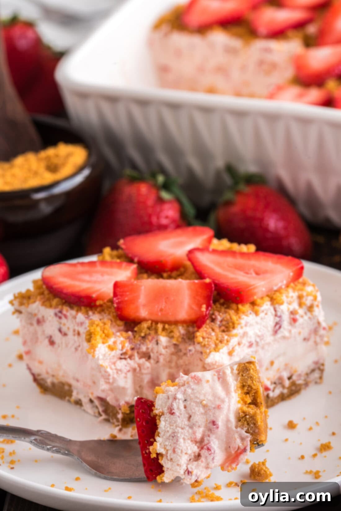 Strawberry Dream Dessert on a fork resting in front of a full slice of Strawberry Dream Dessert on a plate