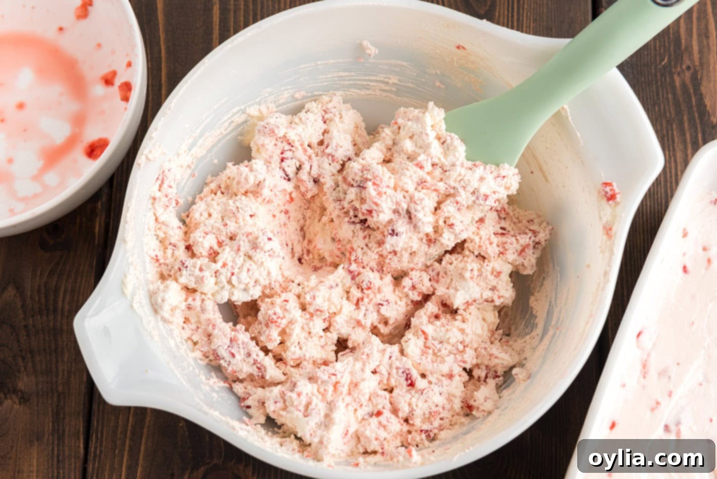 Strawberry chunks folded into Cool Whip in a bowl