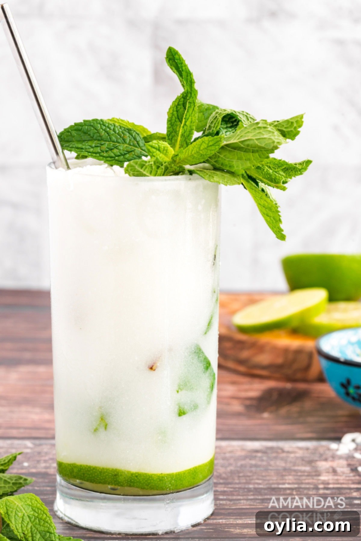 This refreshing Coconut Mojito is made with fresh cooling mint, coconut rum, cream of coconut and club soda. A delicious and tropical cocktail for summer! Close-up of a coconut mojito in a glass, highlighting the layers of ice, mint, and liquid, with a focus on the tropical rum content.