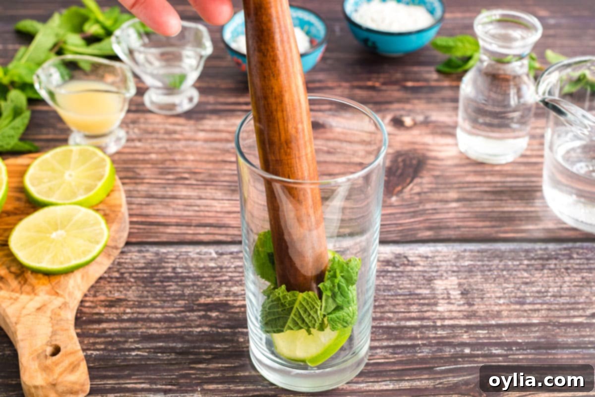 Coconut Mojito Bliss 3 Gently muddling fresh mint leaves and lime wedges in a tall glass to release their aromatic oils and juice.