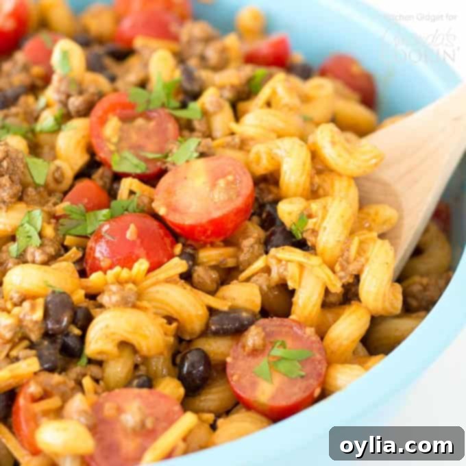 Close-up of a serving bowl filled with a delicious taco pasta salad, highlighting the texture of the pasta, ground beef, beans, and cheese.