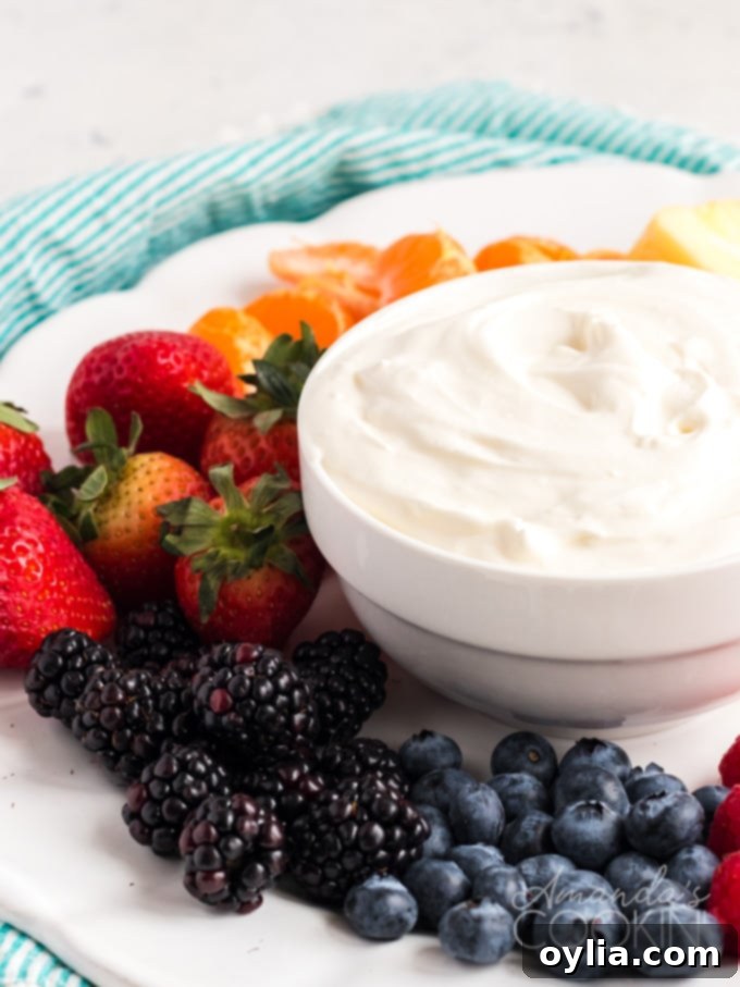 A close-up shot of a white ceramic bowl filled with creamy, light, and fluffy cream cheese fruit dip, ready to be served, sitting on a natural wooden surface.
