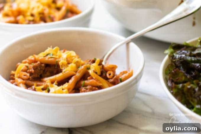A serving of sloppy joe pasta in a white bowl, garnished with fresh parsley