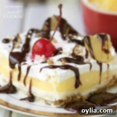 banana split layered dessert with cherry and chocolate drizzle garnish