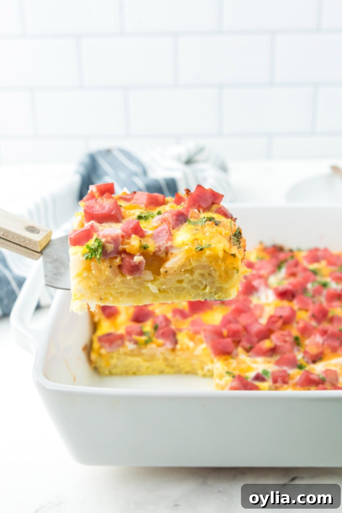 Spatula lifting a generous portion of breakfast casserole, showing the fluffy eggs and melted cheese