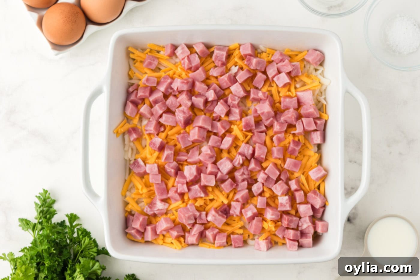 Cubed ham spread over the cheese layer in a casserole dish
