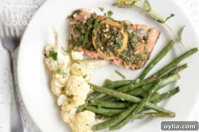 Sheet pan salmon dinner on a plate, garnished with lemon and tarragon