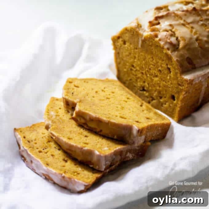 Sliced pumpkin bread with maple glaze on a cutting board, showing moist texture