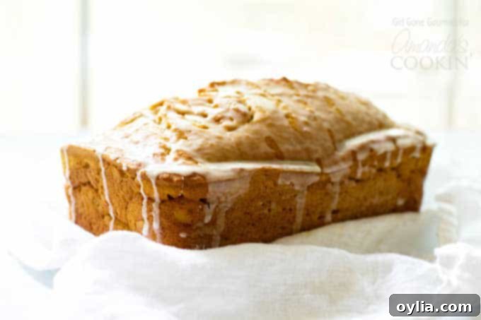 Freshly baked pumpkin bread loaf cooling on a rack, showcasing the maple glaze drizzle