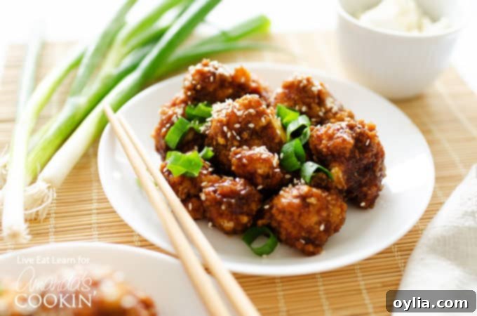A serving of sticky garlic cauliflower with chopsticks, garnished with green onions and sesame seeds.