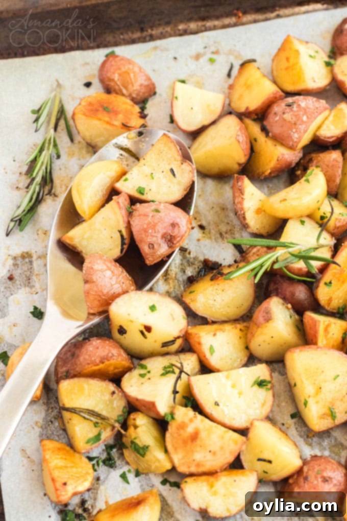Golden crispy roasted potatoes with rosemary and garlic on a baking pan, ready to serve with a spoon
