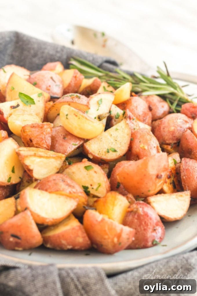 A dish of golden roasted potatoes garnished with fresh rosemary sprigs, ready to be served