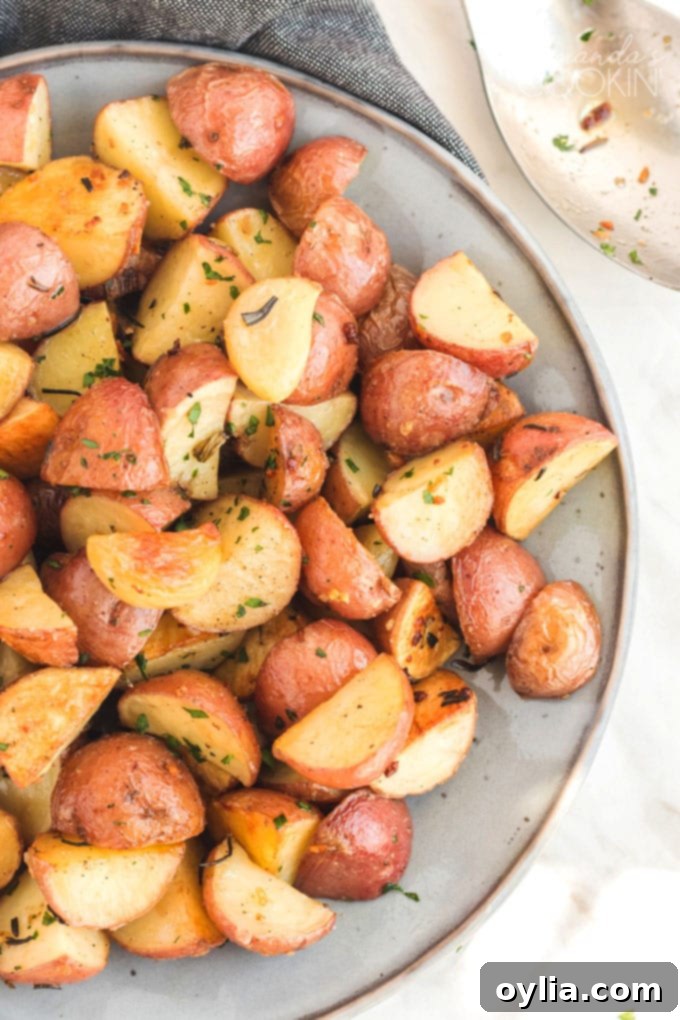 A serving of beautifully roasted potatoes garnished with fresh rosemary on a white plate