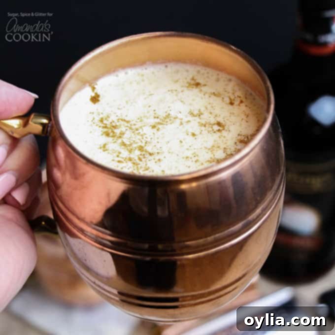 A second, appetizing view of the creamy eggnog cocktail served in a beautiful copper mug, with a sprinkle of nutmeg on top.