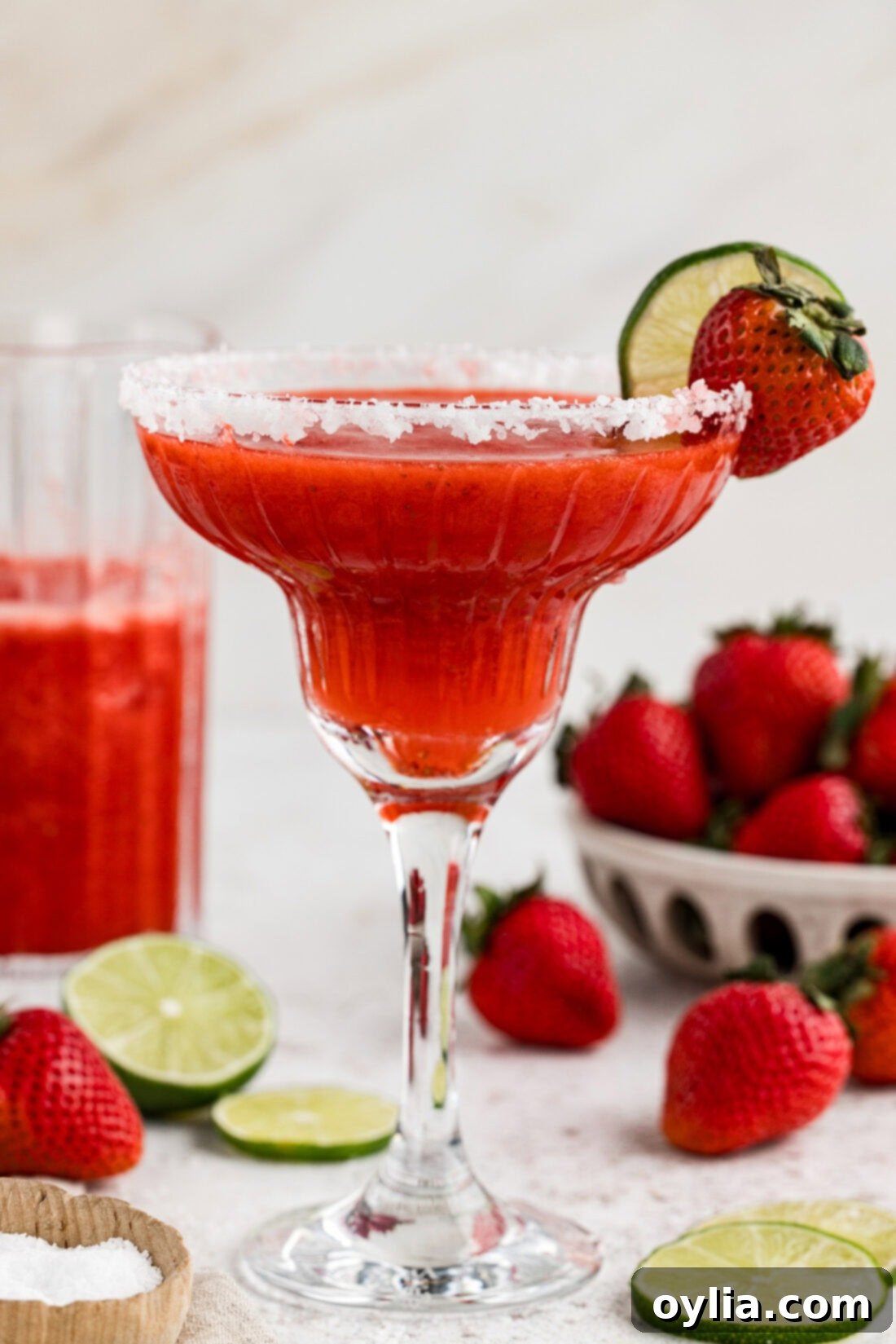 Side view of a Strawberry Margarita garnished with a lime wheel and strawberry