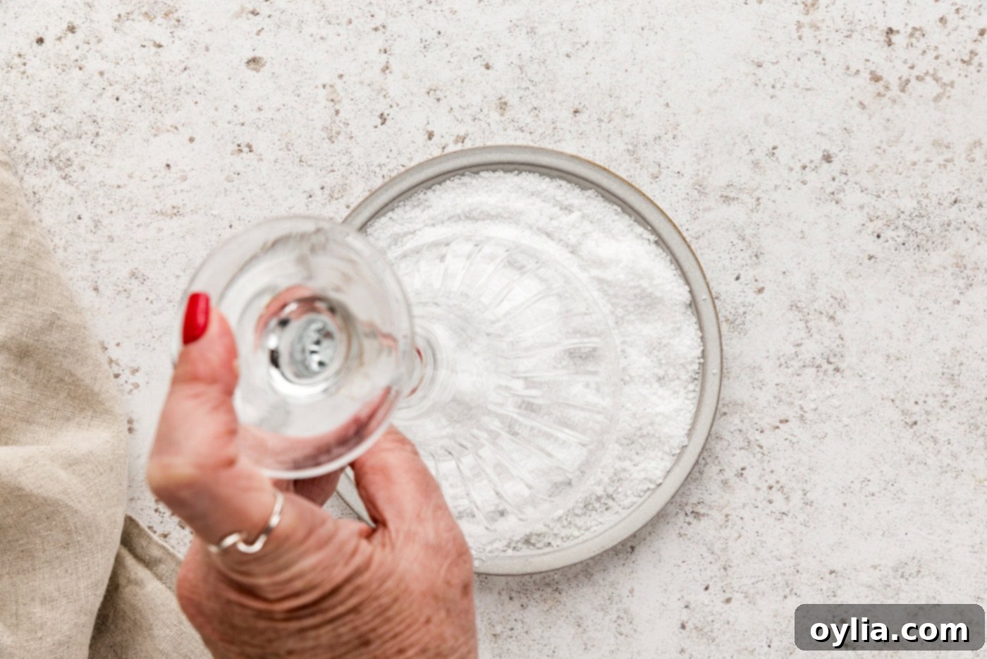 hand holding a martini glass upside down and dipping it in rimming salt