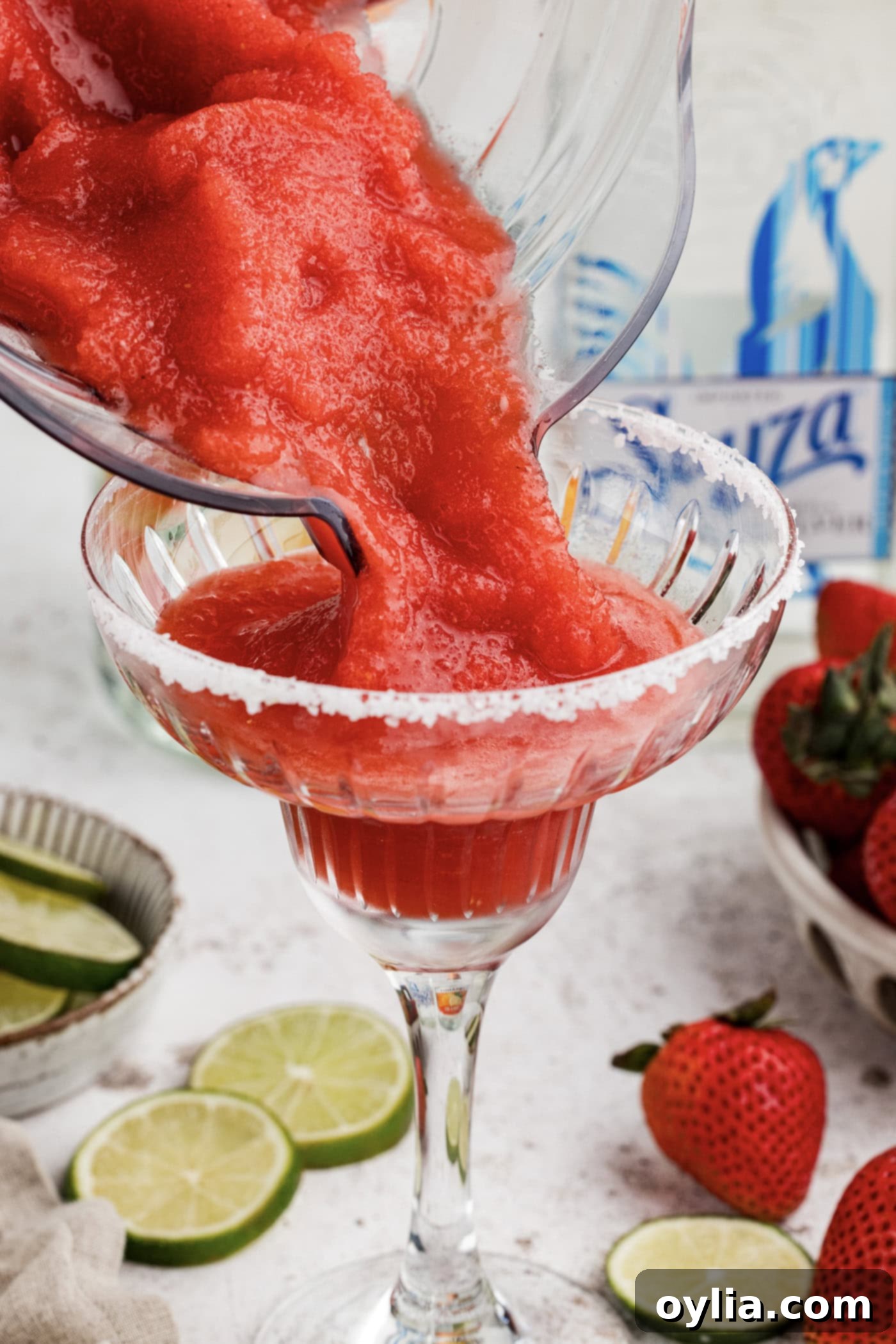 pouring strawberry margarita slush from blender into a glass