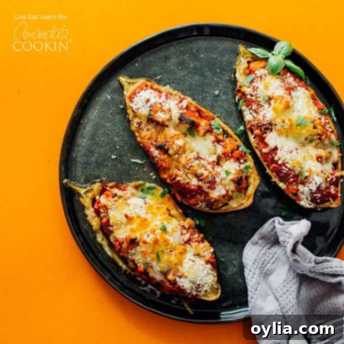 A close-up shot of a baked stuffed eggplant parmesan half, garnished with fresh herbs, highlighting the perfectly melted cheese and golden-brown crispy panko topping.