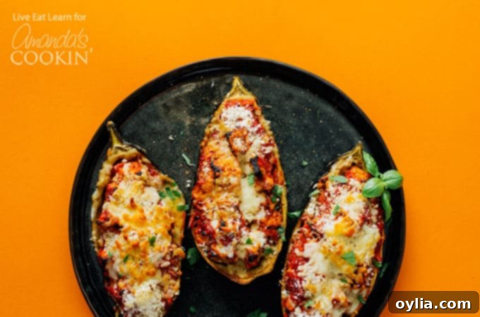 A baking sheet displaying two raw eggplant halves, expertly scored and ready for the flesh to be scooped out, illustrating the preparation step.