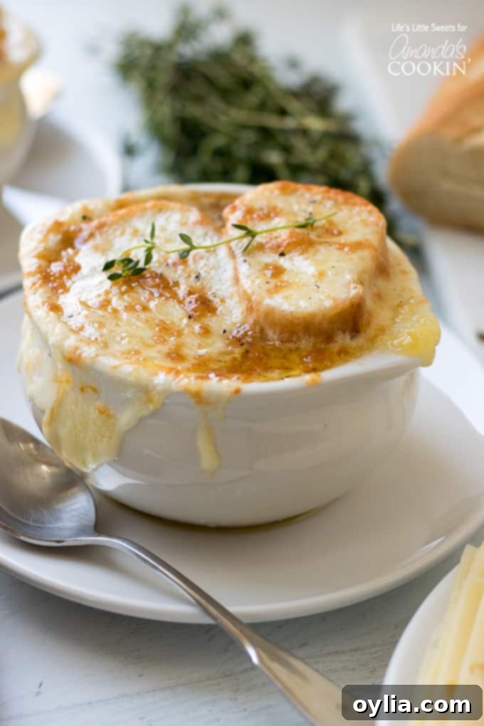 A bowl of cheesy French Onion Soup, garnished with fresh thyme and a golden-brown crust.